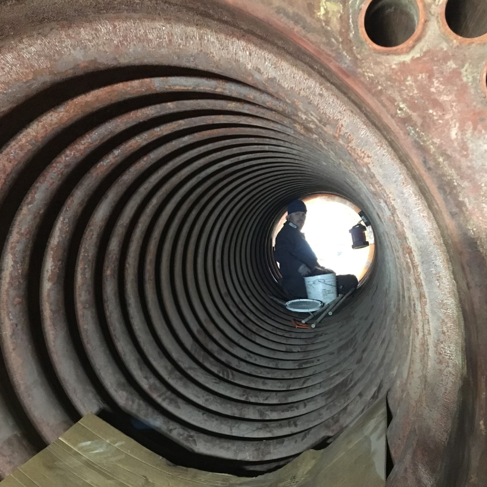 A man sitting inside a massive steel pipe.